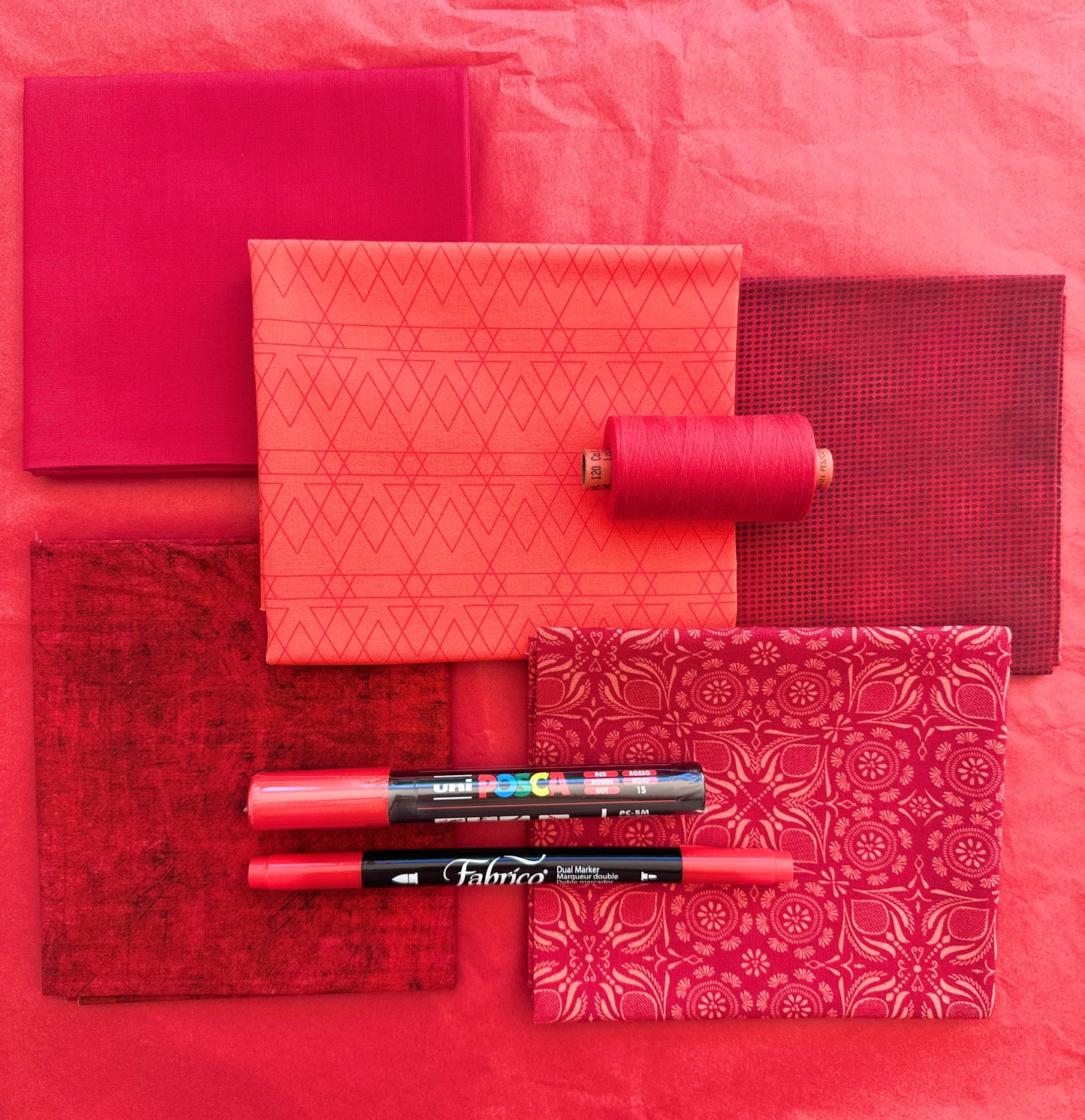 Red rainbow stash builder bundles of quilting fabric in fat quarters with a Posca pen and Fabrico pen.